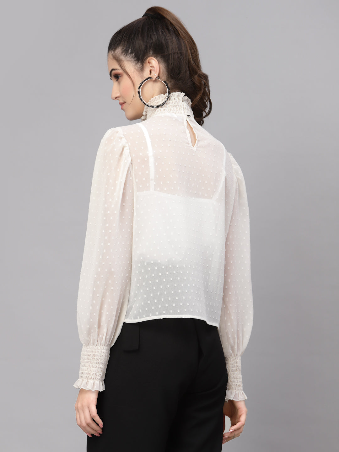 Woman wearing a white top with sheer sleeves on a gray background