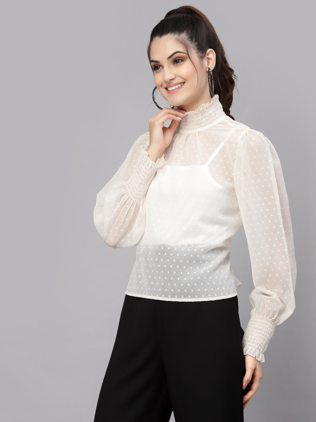 Woman wearing a white top with sheer sleeves on a gray background