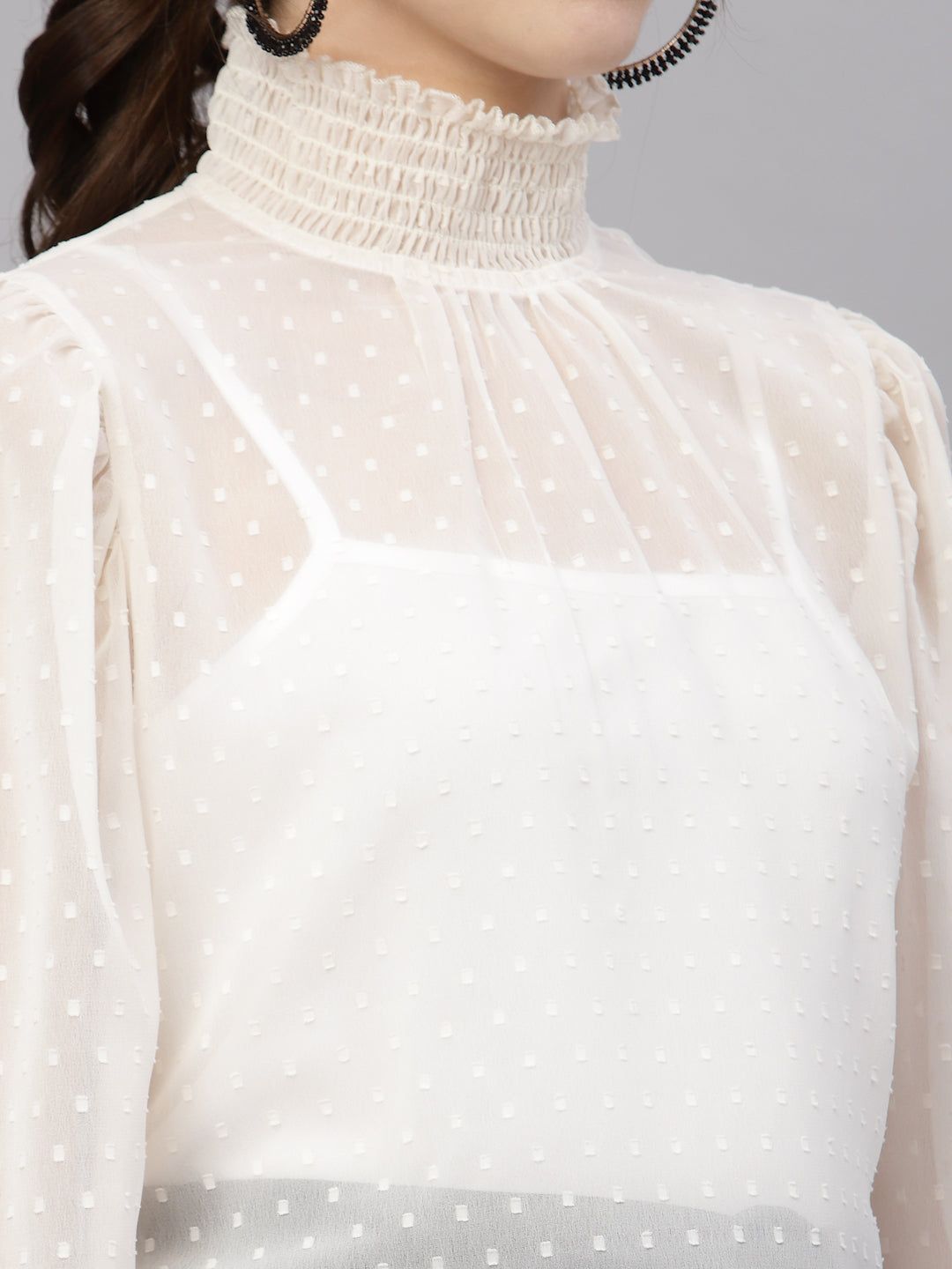 White polka dot top with a high neckline on a gray background