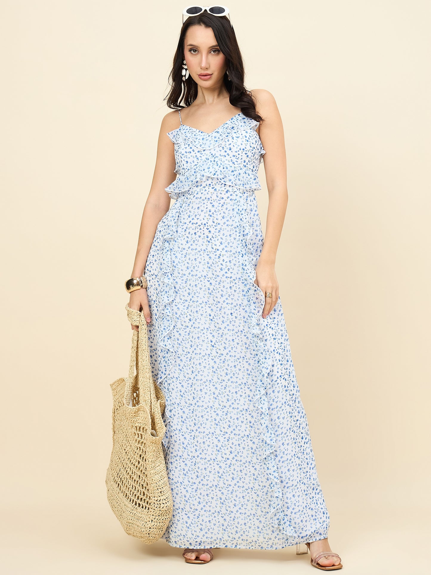 Woman wearing a blue floral dress holding a beige bag on a beige background