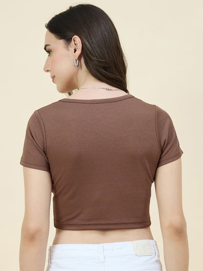 Woman wearing a brown ribbed crop top against a beige background