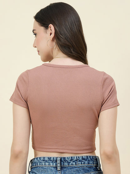 Woman wearing a cream ribbed crop top and blue jeans on a beige background