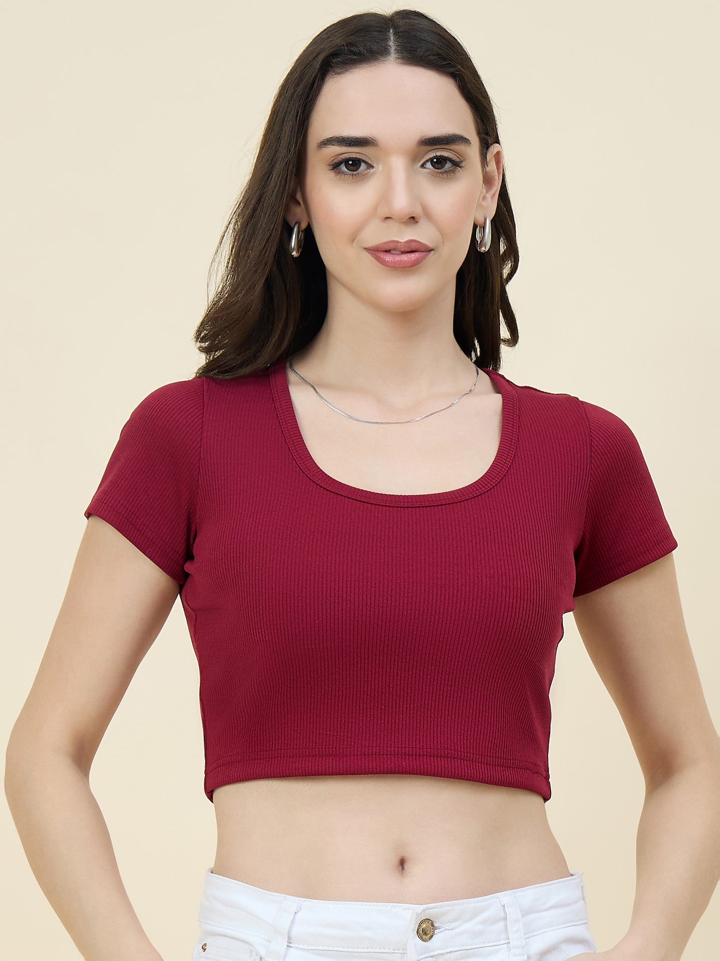 Woman wearing a maroon crop top against a beige background