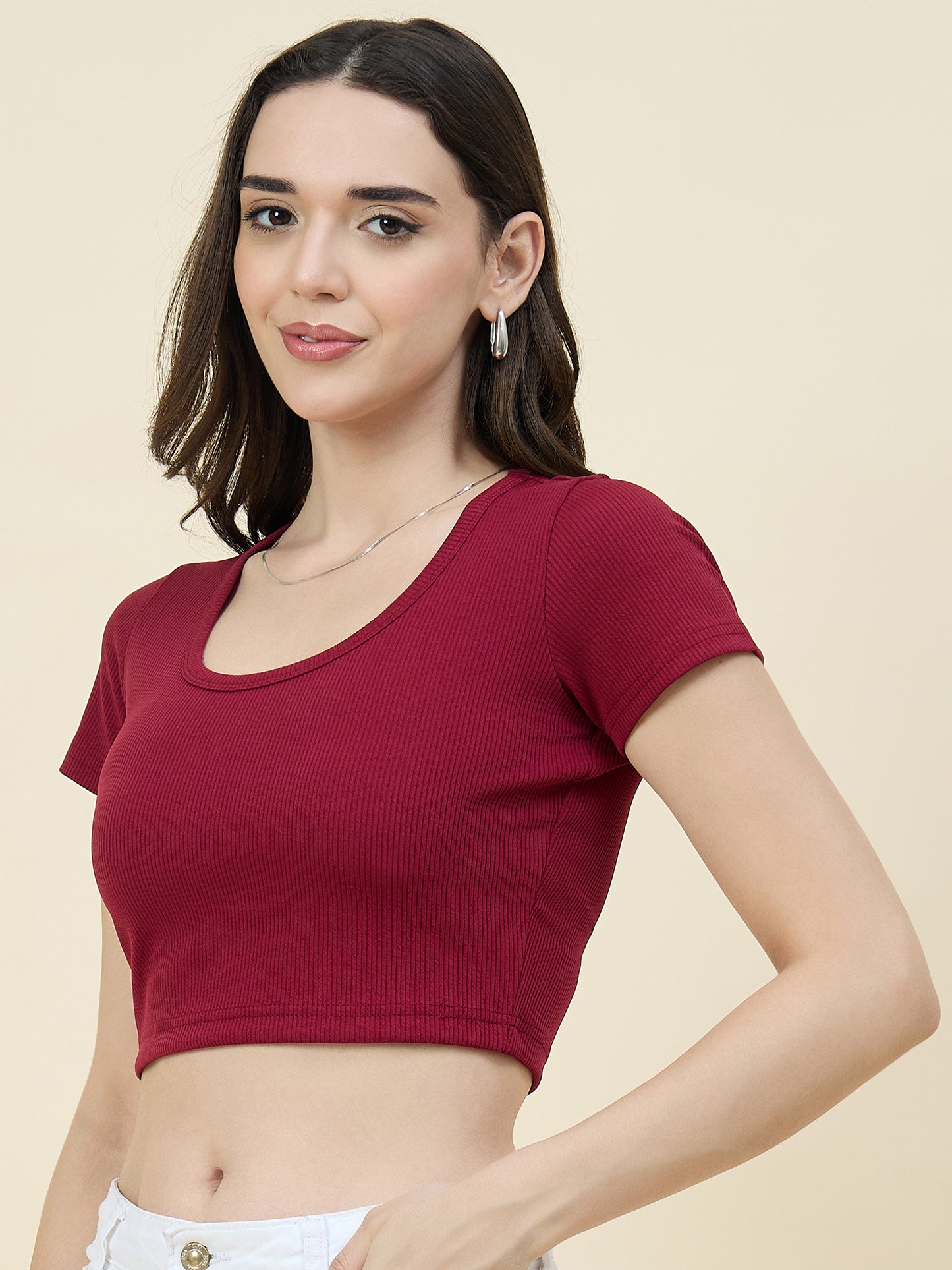 Woman wearing a maroon crop top against a beige background