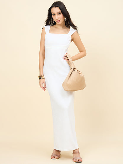 Woman in a white dress holding a beige handbag against a beige background