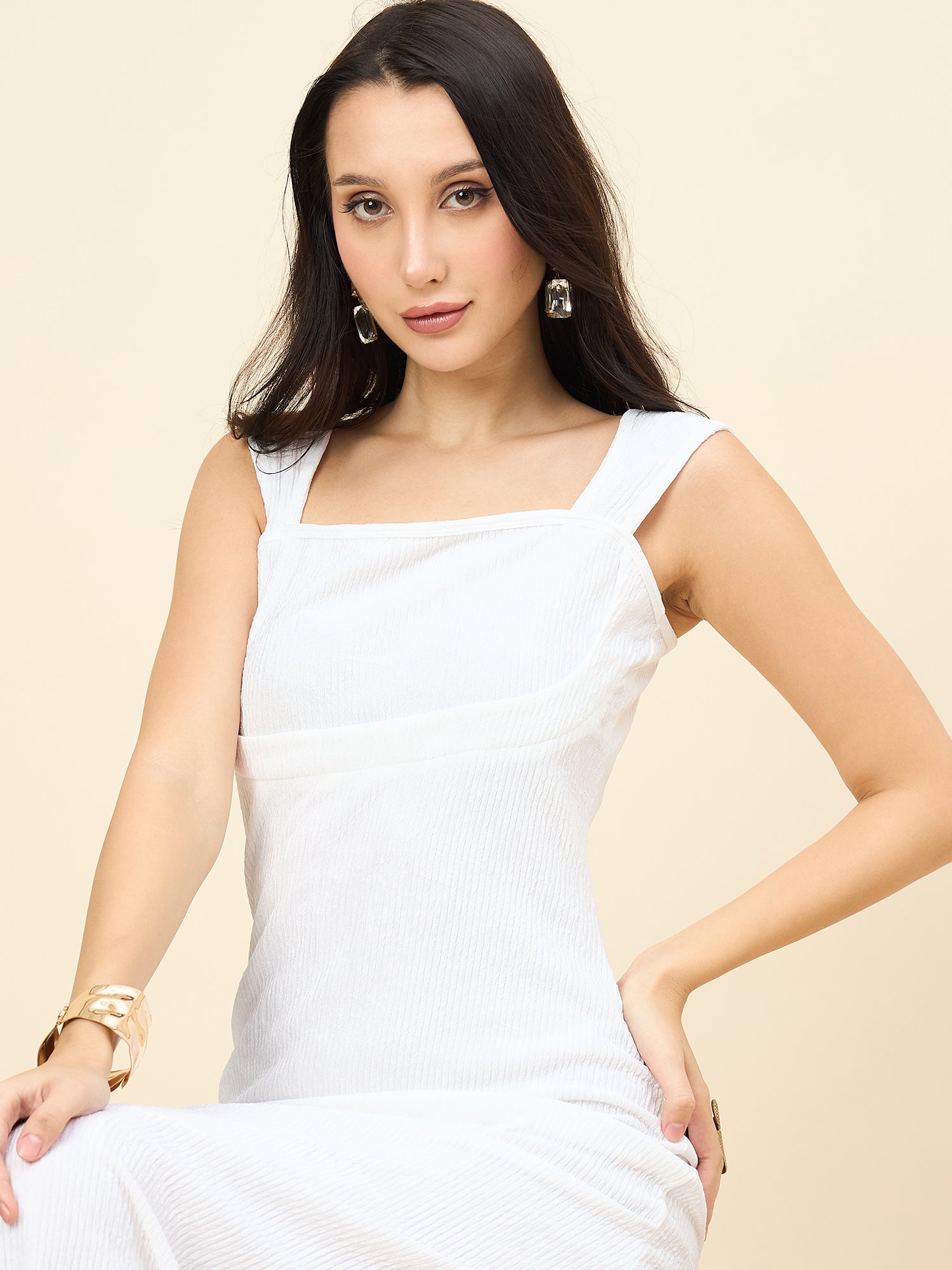 Woman wearing a white dress against a beige background