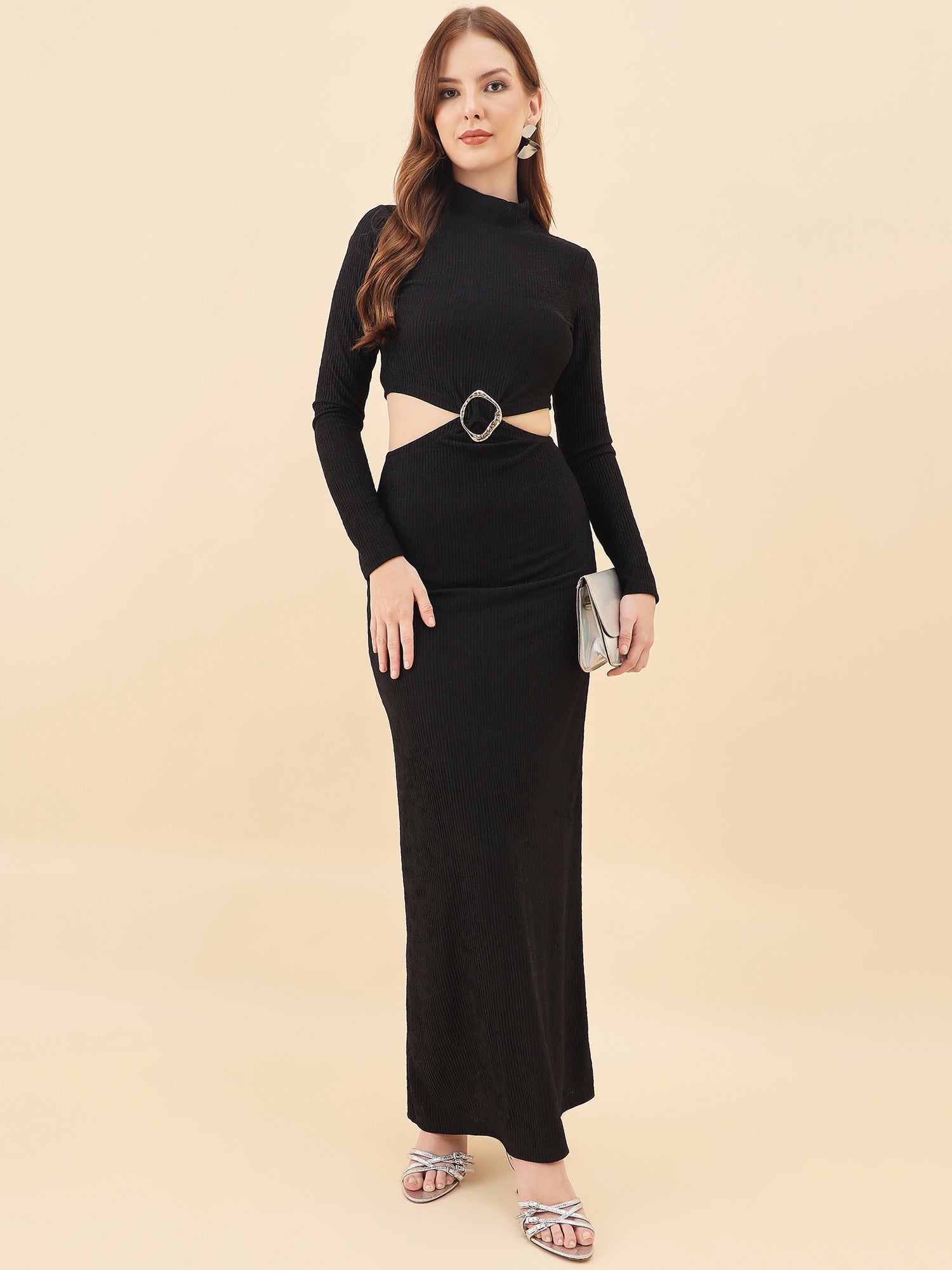 Woman wearing a black long-sleeve top and black skirt with a belt on a beige background