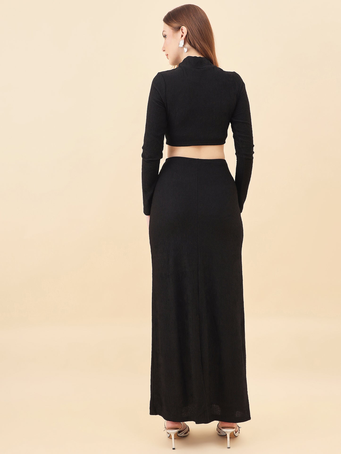 Woman wearing a black long-sleeve top and black skirt on a beige background