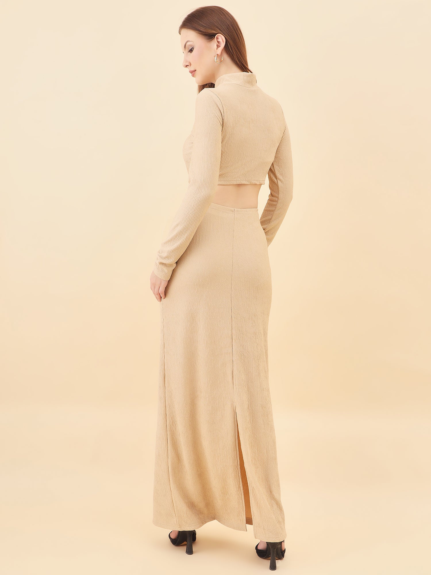 Woman wearing a beige long dress with a slit on a beige background