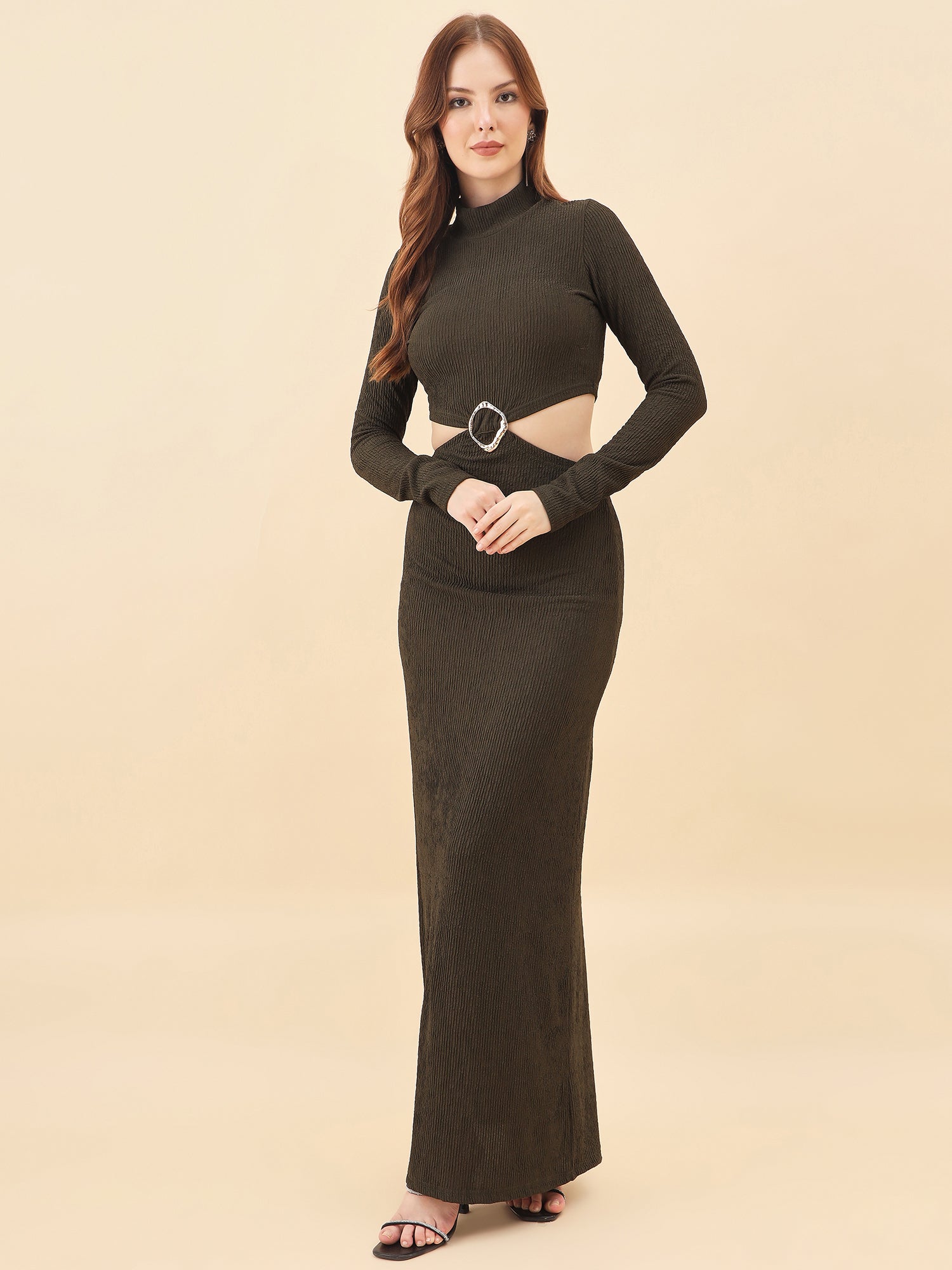 Woman wearing a long dark green dress with a cutout design on a beige background