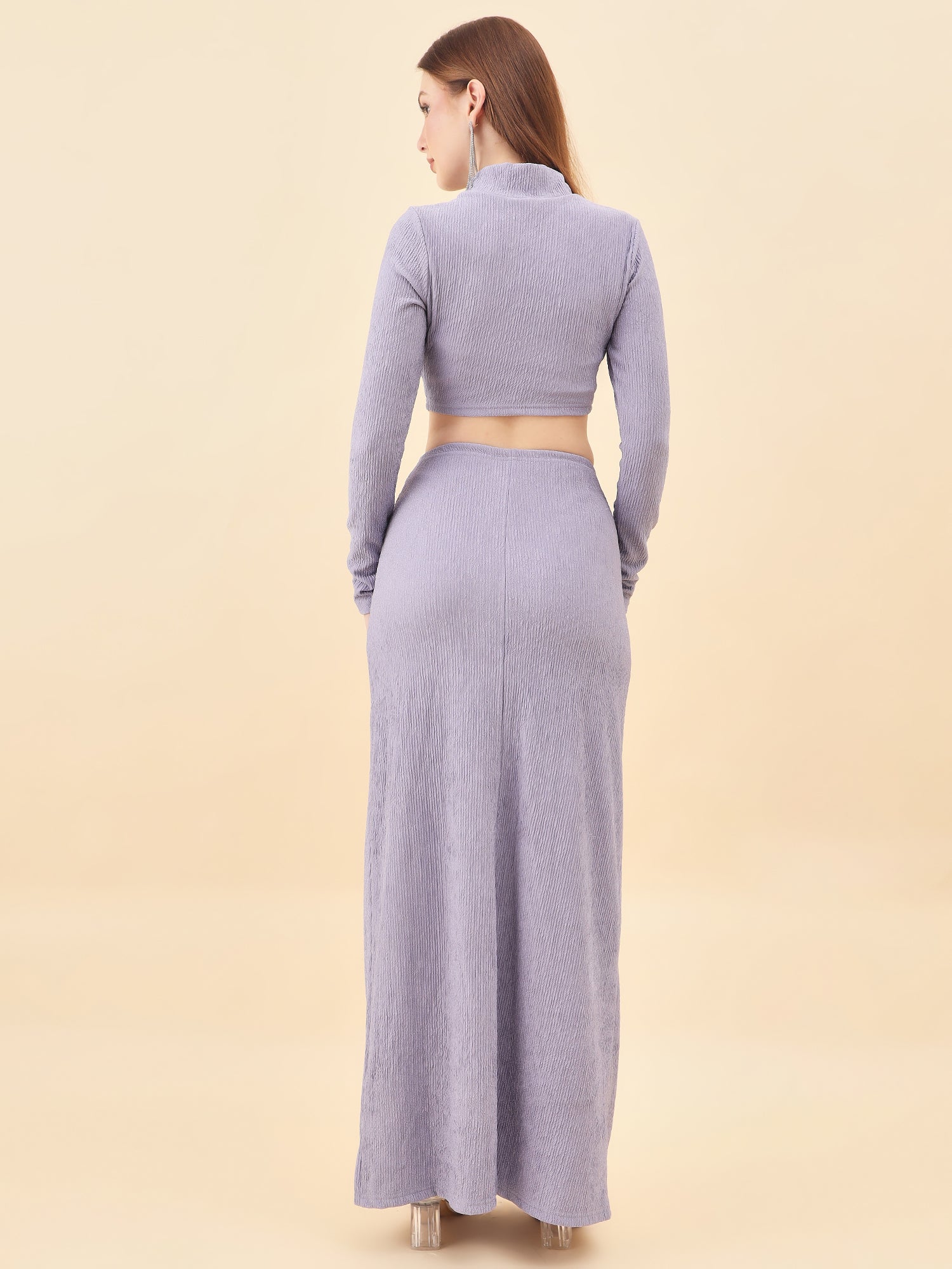 Woman wearing a long-sleeve crop top and maxi skirt set on a beige background