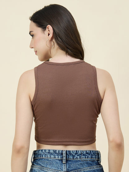 Woman wearing a brown ribbed crop top and blue jeans on a beige background