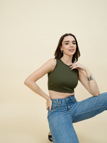 Woman wearing a green tank top and blue jeans against a beige background