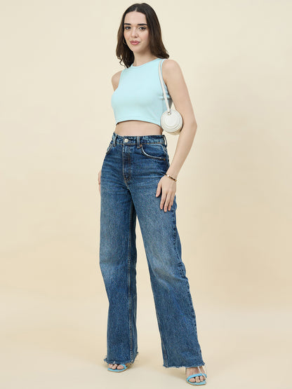 Woman wearing a Sky blue sleeveless top and blue jeans against a beige background