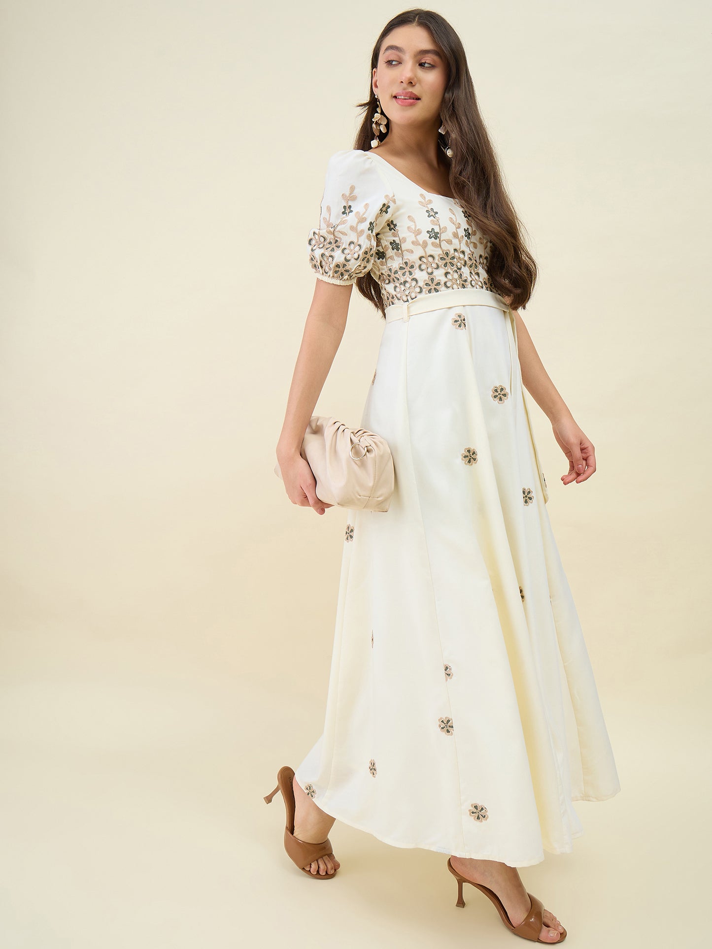 Woman wearing a white outfit with floral embroidery on a beige background