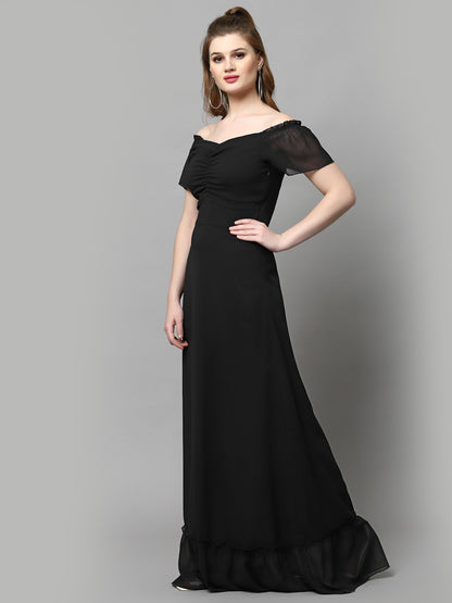A woman modeling a solid black maxi dress with a V-neck neckline and short sleeves. The dress has a maxi skirt length and is presented on a plain background.