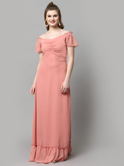 A woman wearing a peach-colored, V-neck, short-sleeved maxi dress with pleated detail and ruffled accents.