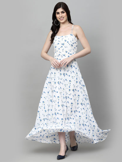 A woman wearing a white maxi dress with blue floral print and thin straps, standing against a grey background.