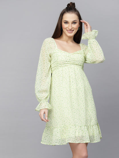 A woman wearing a green, floral, short-sleeved, fit-and-flare dress with an adjustable strap.