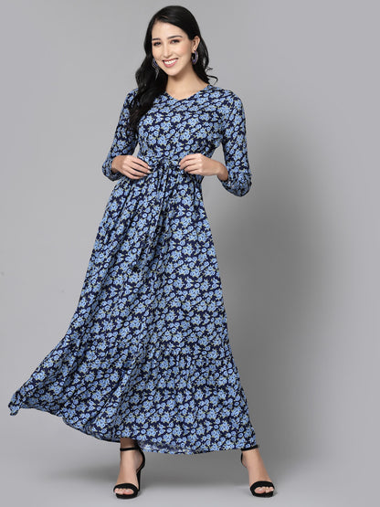 A woman modeling a floral print dress with a flowing design, in shades of blue and black.