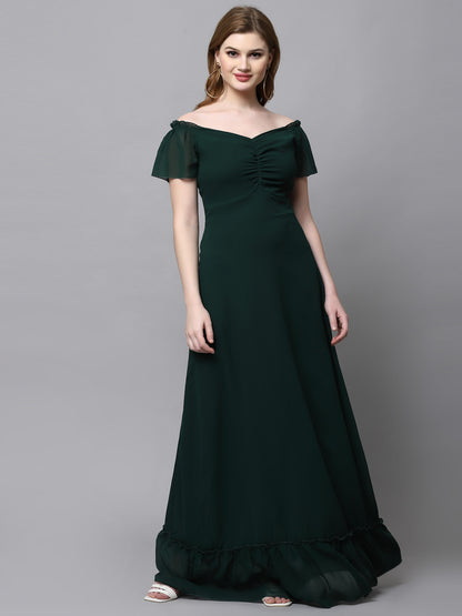 A woman wearing a green maxi dress with short puffed sleeves and a V-neckline.