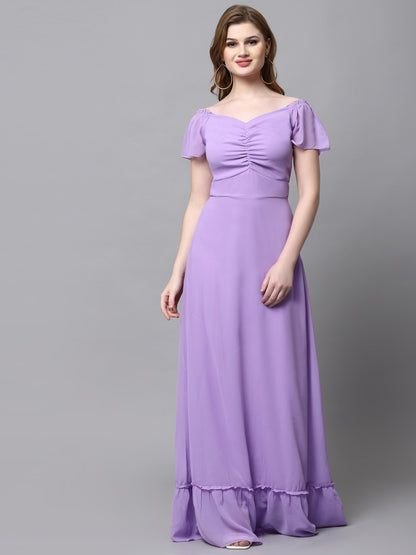 A woman wearing a solid purple maxi dress with a V-neckline and long sleeves.