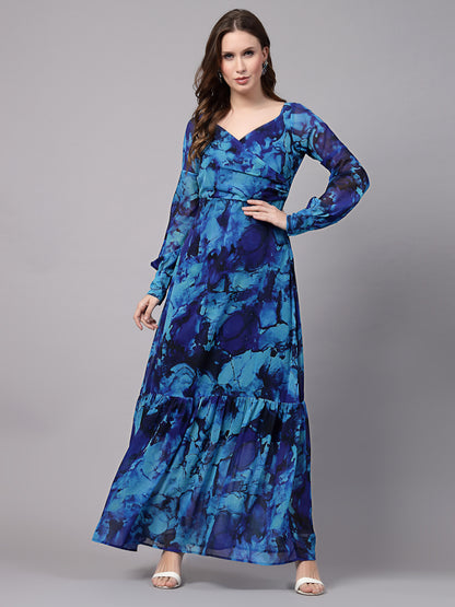 A woman wearing a blue maxi dress with a geometric print, long sleeves, and a V-neckline.