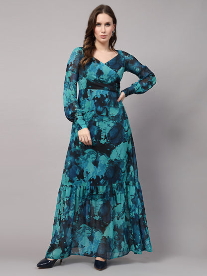 A woman wearing a green maxi dress with a geometric print, long sleeves, and a V-neckline.