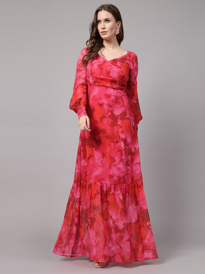 A woman wearing a red maxi dress with a floral print, standing against a plain background.